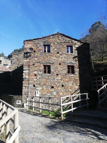 an old stone building with windows and a fence at Casa das Tias in Lousã