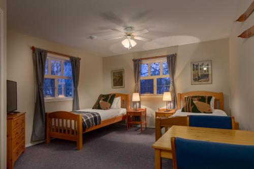 レベルストークにあるCourthouse Inn Revelstokeのベッドルーム1室(ベッド2台、テーブル、椅子付)