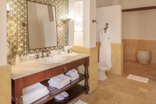 a bathroom with a toilet, sink, mirror and bath tub at Hotel Casa San Agustin in Cartagena de Indias