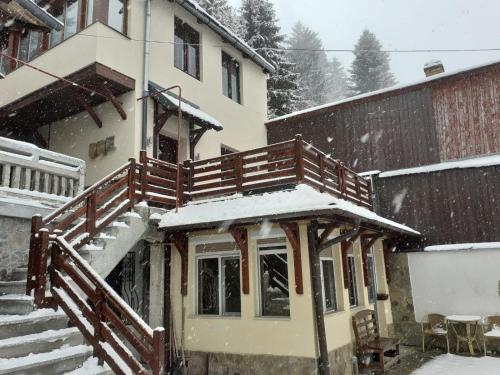 a house with a snow covered porch and stairs at Old Bakery House in Sinaia
