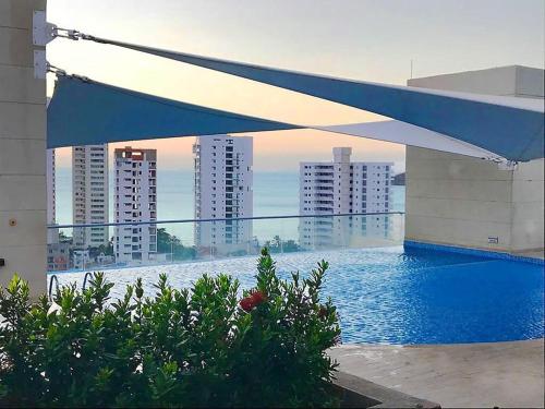 a blue and white umbrella over a swimming pool with buildings at Velas Al Mar - Apartamento Rodadero Gaira in Gaira