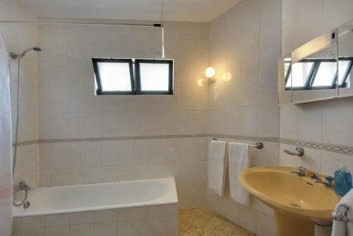 a white bathroom with a tub and a sink at VILLA COELHO in Albufeira
