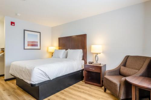 Habitación de hotel con cama y silla en Red Lion Inn & Suites Des Moines, en Des Moines