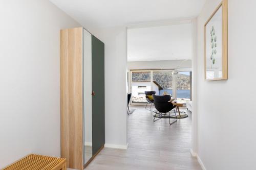 a hallway with a door to a living room with chairs at Funky cabin with a panoramic view of the Oslofjord in Nordre Frogn