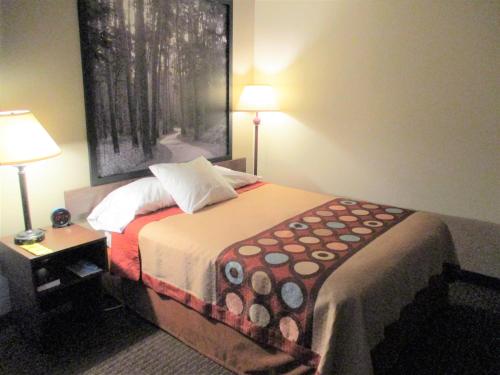 a bedroom with a bed with two lamps and a painting on the wall at Super 8 by Wyndham Bemidji MN in Bemidji