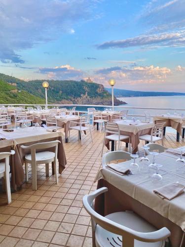 Un restaurante con mesas y sillas blancas y el océano. en Il Romito, en Quercianella