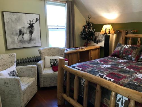 a bedroom with a bed and chairs and a christmas tree at Holiday Lodge Bed and Breakfast in Banff