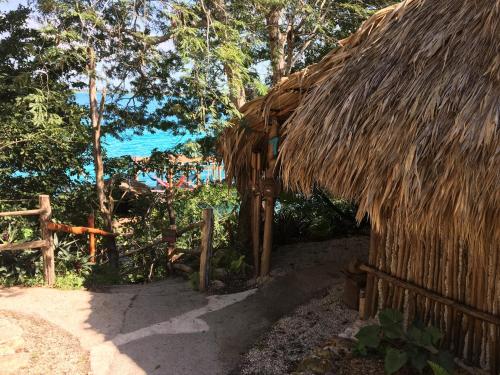 a hut with a straw roof and a fence at Casa Lamat in Bacalar