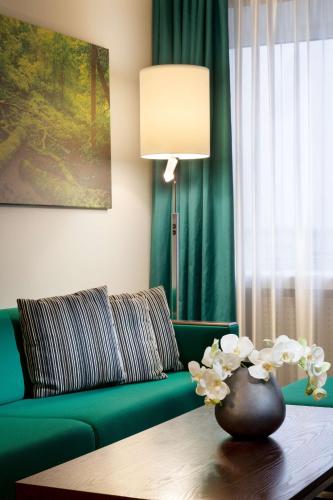 a living room with a green couch and a table at Radisson Blu Hotel Olümpia in Tallinn