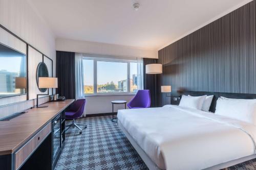 ein Hotelzimmer mit einem großen Bett und einem Schreibtisch in der Unterkunft Radisson Blu Hotel Amsterdam Airport, Schiphol in Schiphol