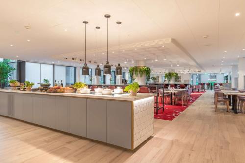 史基浦Radisson Blu Hotel Amsterdam Airport, Schiphol的一个带长台面和桌椅的大厨房