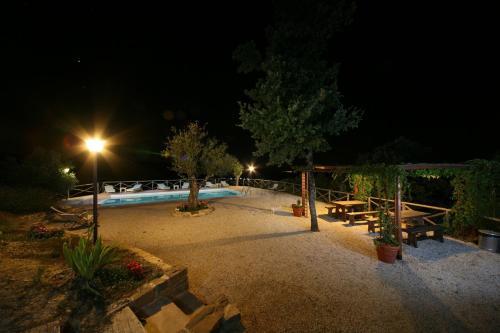 una piscina notturna con tavolo e panche di Agriturismo Monte Valentino a Pietralunga