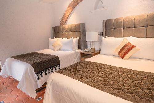 a hotel room with two beds and a mirror at Casa Eva Hotel Boutique & Spa in Cholula