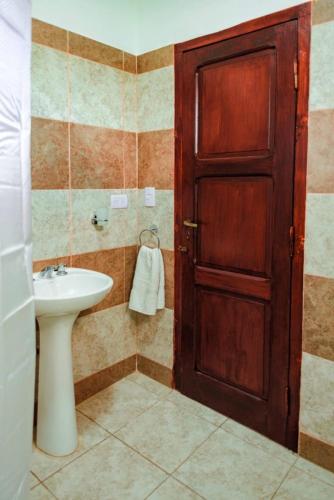 a bathroom with a sink and a wooden door at Cabañas Villa del Sol in Salta