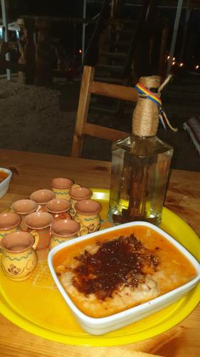 a plate with a bowl of food and a bottle on a table at Pensiunea Agroturistica Cerna, Vaideeni - Polovragi in Vaideeni