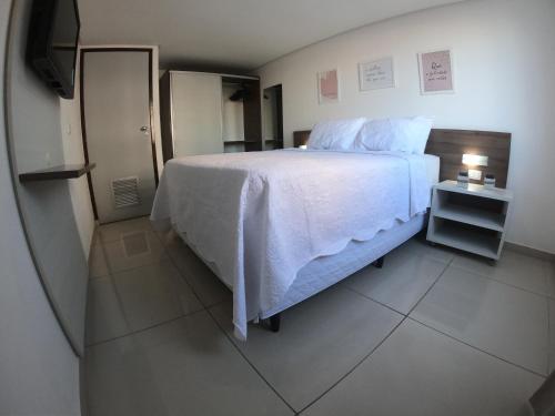sypialnia z białym łóżkiem i telewizorem w obiekcie Imperial Flat w mieście João Pessoa