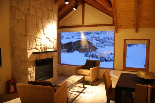a living room with a fireplace and a table and chairs at Galileo Boutique Hotel in San Carlos de Bariloche