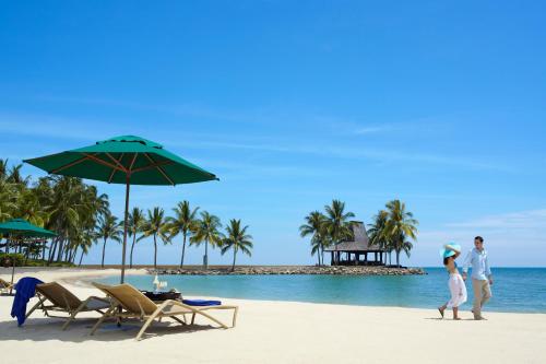 a man and a woman walking on the beach at Shangri-La Tanjung Aru, Kota Kinabalu in Kota Kinabalu