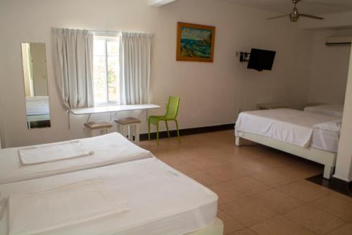 a bedroom with two beds and a table and a window at Hotel Olinalá Diamante in Acapulco