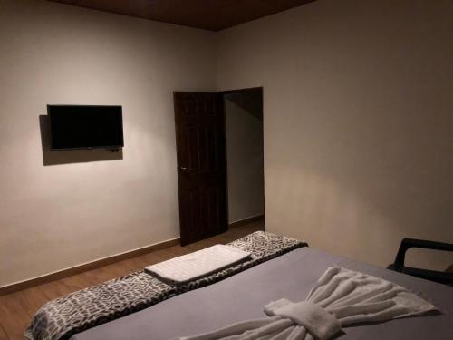 a bedroom with a bed and a flat screen tv at Hostal DEYLUWIN in Juayúa