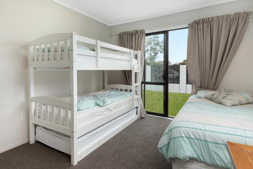 a bedroom with two bunk beds and a bed at The Mount Beach Pad - Mt Maunganui Holiday Home in Matapihi