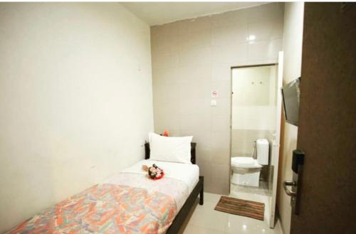 a small bedroom with a bed and a toilet at Permata Inn in Medan