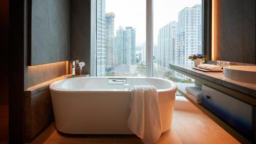 釜山的住宿－Signiel Busan，带浴缸、水槽和窗户的浴室