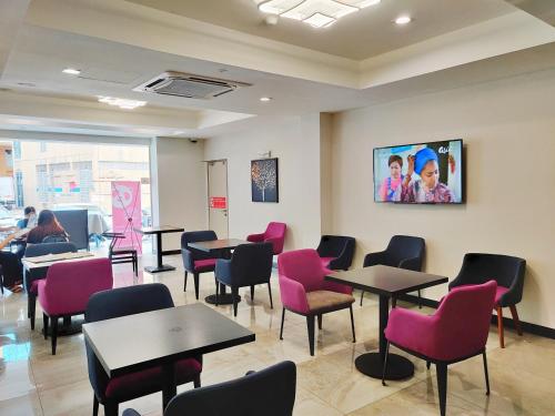 una sala d'attesa con tavoli e sedie rosa di Meriton Inn a Kuantan