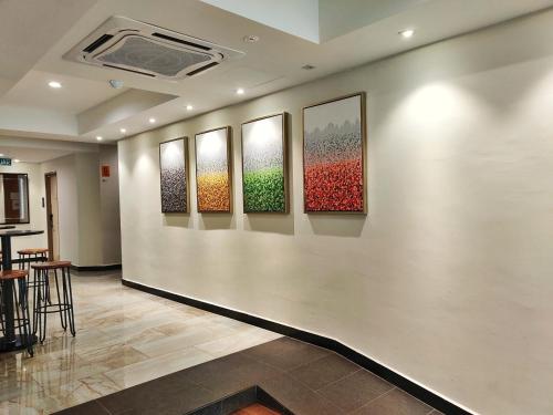 a hallway with four paintings on a wall at Meriton Inn in Kuantan