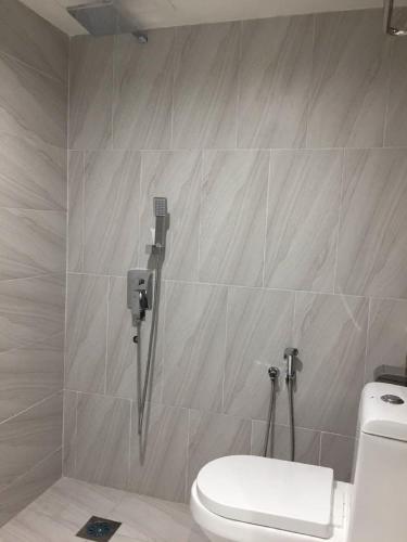 a bathroom with a toilet and a tile wall at Meriton Inn in Kuantan
