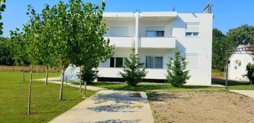 a white house with trees in front of it at Riviera Inn apartments in Ulcinj