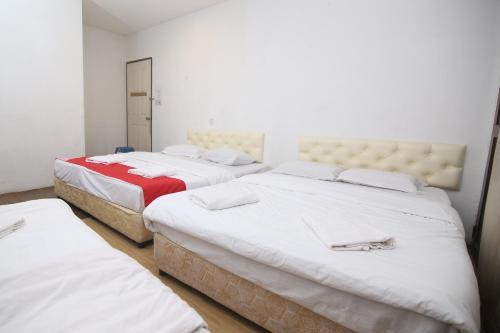 een kamer met 3 bedden met witte lakens bij L&C Premium Stay in Kuching