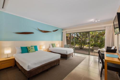 a hotel room with two beds and a desk with a desk at Ballina Beach Resort in Ballina