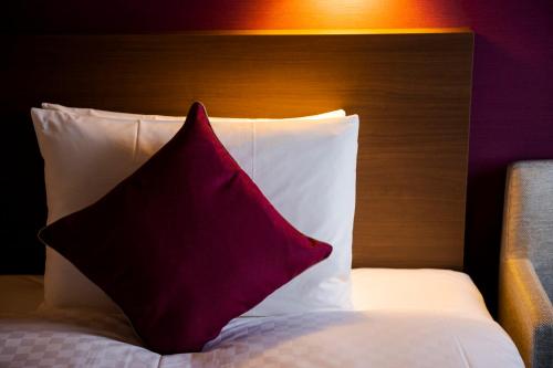 a red pillow sitting on top of a bed at Best Western Plus Fukuoka Tenjin-minami in Fukuoka