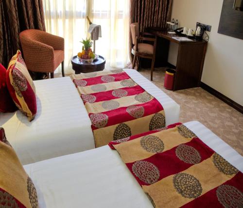 a hotel room with two beds and a desk at Boma Inn Eldoret in Eldoret