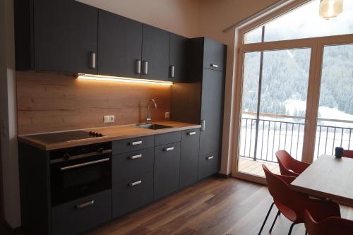 a kitchen with black cabinets and a table and a window at Unterbergerhof in Val di Vizze