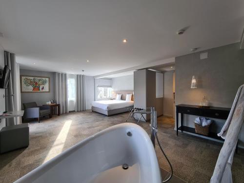 - une salle de bains avec baignoire et un lit dans une chambre dans l'établissement Maison Jenny Hotel Restaurant & Spa, à Hagenthal-le-Bas
