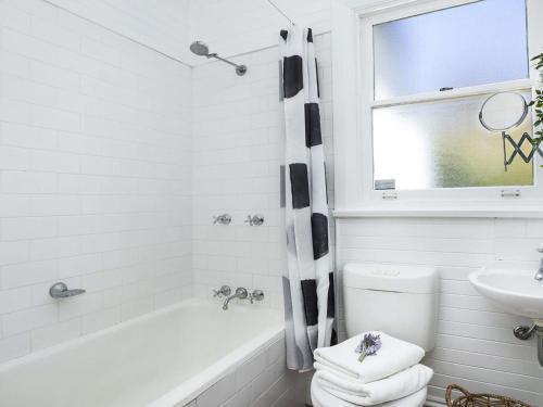 a white bathroom with a tub and a sink at Bourne Cottage - Perfect for all seasons in Mittagong