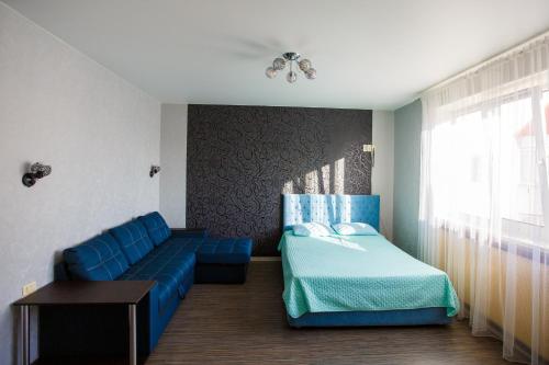 a bedroom with a blue couch and a bed at Liproom Apartments on Smorodina in Lipetsk