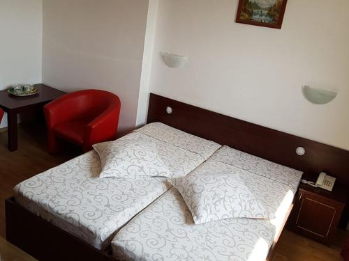 1 dormitorio con 1 cama y 1 silla roja en Hotel Uranus, en Bucarest