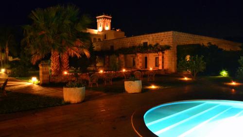 a building with a clock tower and a swimming pool at night at Masseria Incantalupi in San Vito dei Normanni