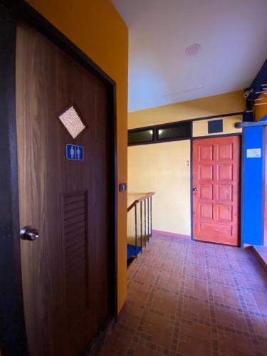 a hallway with a red door and a staircase at At Home Hostel, Pak Chong in Pak Chong
