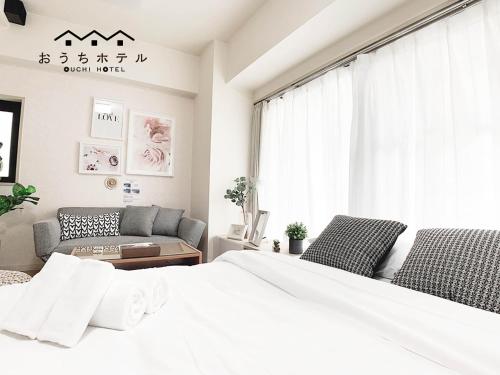 a bedroom with a white bed and a couch at OUCHI HOTEL Takaramachi in Hiroshima
