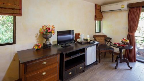 a living room with a table and a tv at Yaang Come Village Hotel - SHA Extra Plus in Chiang Mai