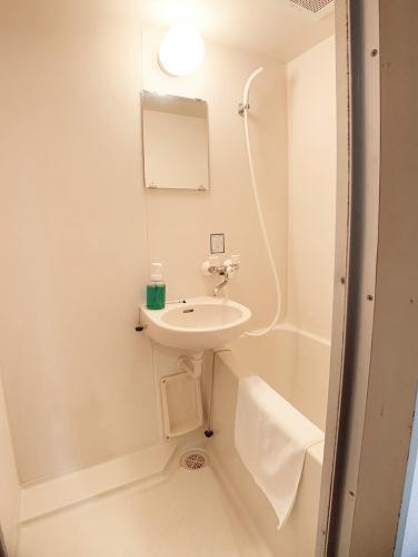 a white bathroom with a sink and a bath tub at OUCHI HOTEL Takaramachi in Hiroshima