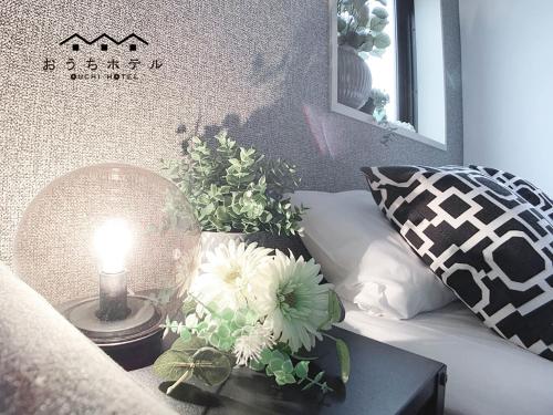 a table with a lamp and flowers on a bed at OUCHI HOTEL Takaramachi in Hiroshima