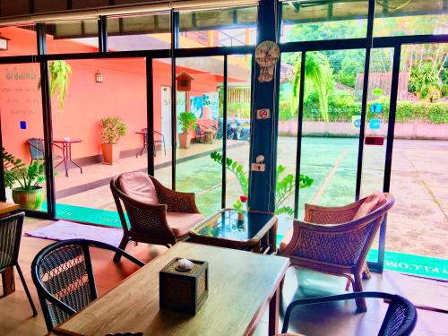 a restaurant with chairs and a table and windows at Chat House Soi 18 Mithuna Chiangrai in Chiang Rai