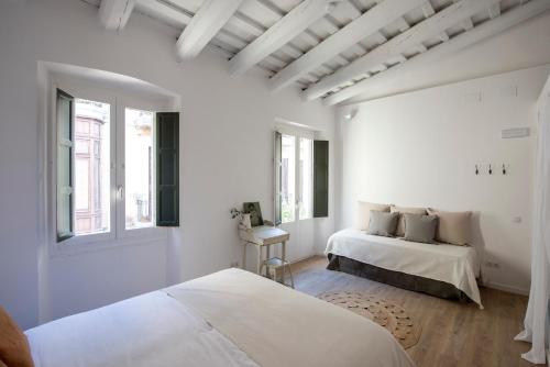 a white bedroom with two beds and a window at CASA FILOMENA in Barcelona