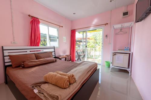 a bedroom with a large bed with pink walls at บ้านสวนวารินทร์ รีสอร์ท in Pak Chong