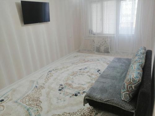 ein Schlafzimmer mit einem Bett mit einer Decke darauf in der Unterkunft Уют в Авангарде in Atyrau